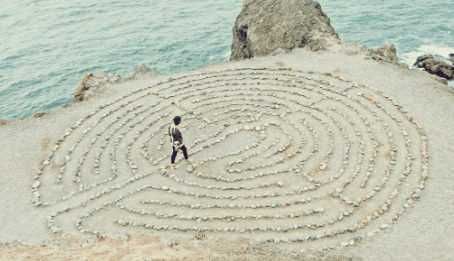 Labirinto di pietre sulla spiaggia vista dall'alto, simbolo di meditazione e introspezione, ambiente naturale, relax e riflessione spirituale, ideale per momenti di calma e concentrazione.