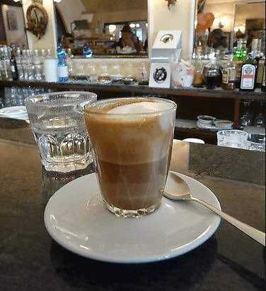 Una tazza di caffè con schiuma in un bar accogliente, ideale per una pausa relax e ristoro.