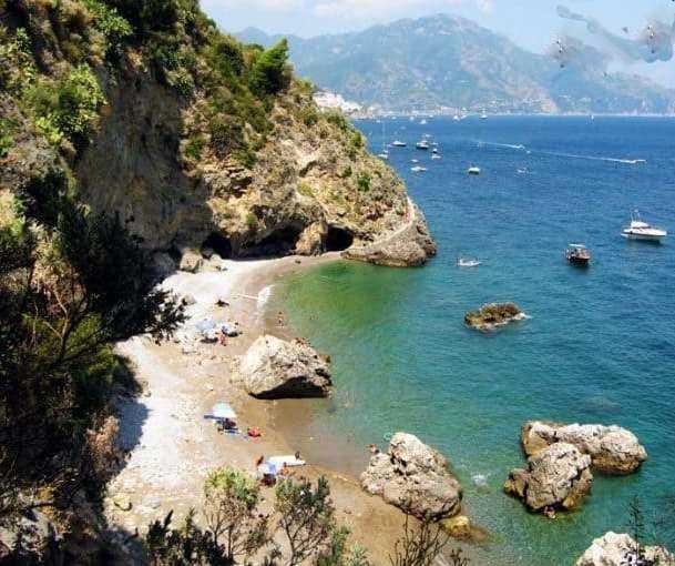 Spiaggia nascosta tra scogli e acque cristalline della Costiera Amalfitana, perfetta per una giornata rilassante e panorami mozzafiato.