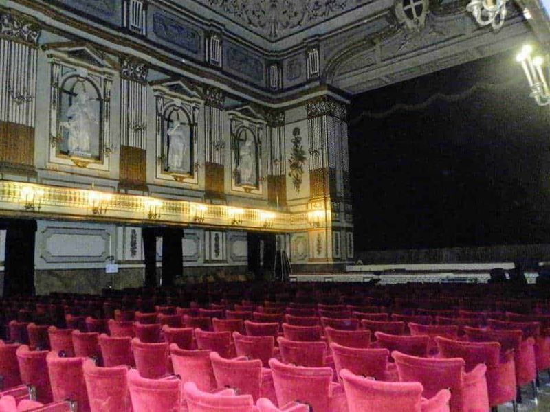 Luxury historic theater interior with ornate wall decorations and red velvet seats for performances and concerts.