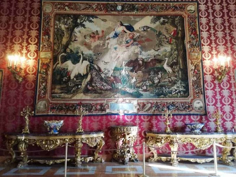 Lusso e arte in uno stile barocco con grande arazzo con figure mitologiche e ornamenti dorati, creando un ambiente elegante e storico.
