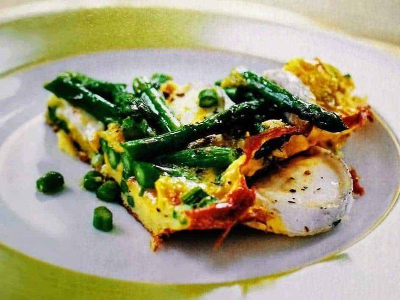 Germogli verdi 6 piatti e insalate con una manciata di semi freschi 3 Uova strapazzate con asparagi e piselli, servite in un piatto bianco elegante, ideale per colazioni e brunch salutari. Ricetta semplice e ricca di verdure fresche e proteine.