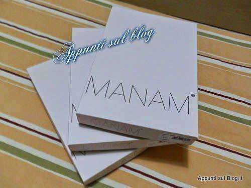 Manam skincare box, prodotto di cosmetici naturali per la cura della pelle, packaging elegante e minimalista, su tavola a righe multicolore.