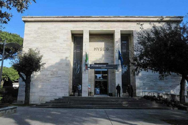 Museo storico con ingresso imponente, scale e bandiere all’esterno, circondato da alberi, rappresenta un punto di riferimento culturale e storico.