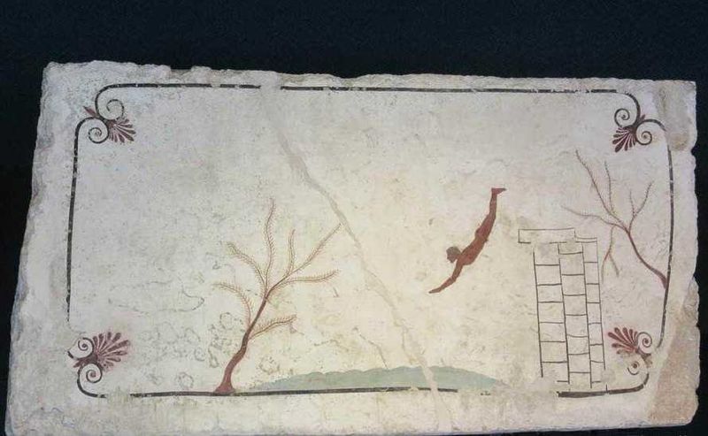Caduta di un uomo da una parete di un palazzo, con alberi e scritte antiche sullo sfondo, su un muro di pietra antica, all'aperto, scenario storico e urbano.