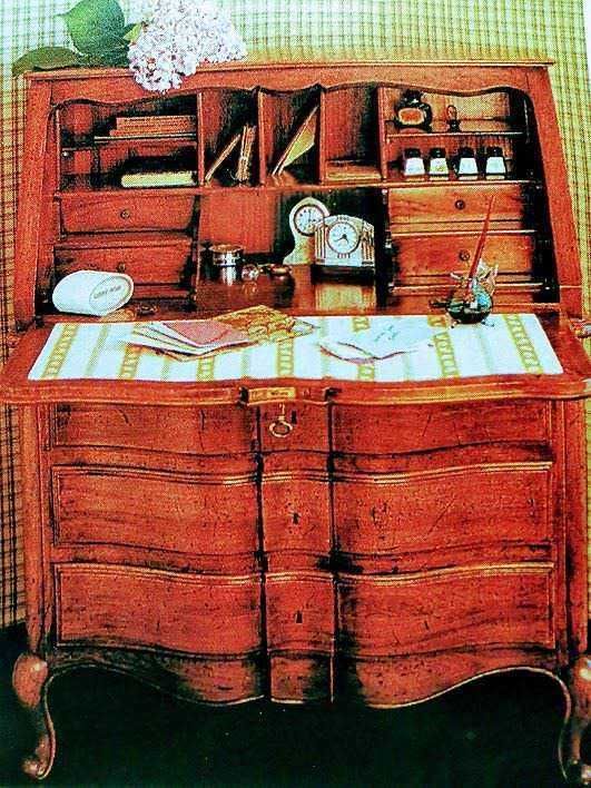 Vetrina o scrittoio in legno antico con scomparti e mensole, decorato con oggetti da scrittura, libri e piante, perfetto per studio o ufficio a tema vintage e shabby chic.