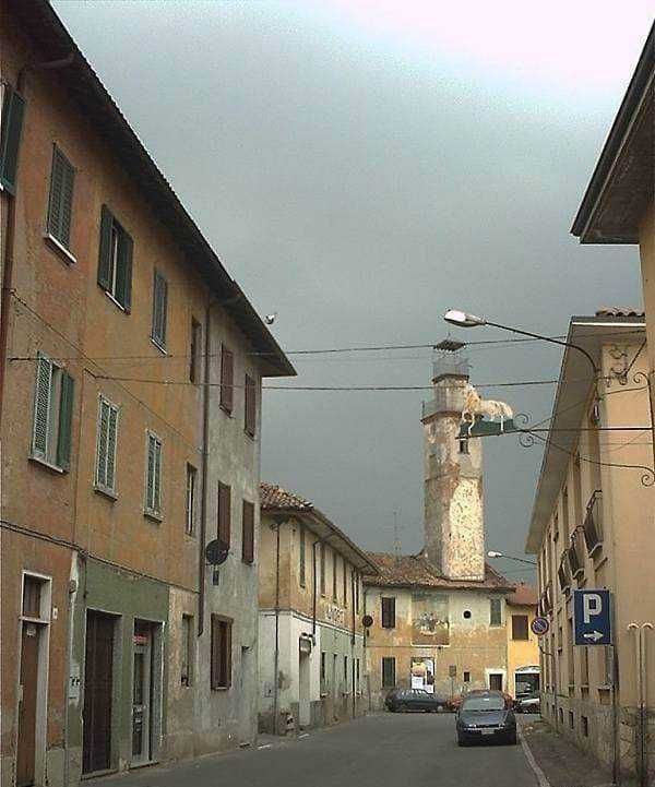 Cielo grigio sopra un vicolo di case storiche con camino in mattoni, atmosfera urbana rilassata, immagini di un angolo di Italia ricco di storia e poesia.
