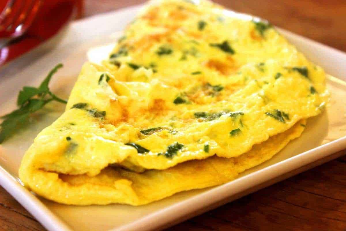 Frittata con erbe fresche servita su piatto bianco, ricetta semplice e gustosa, perfetta per colazione o brunch, ingredienti naturali e stile casalingo.