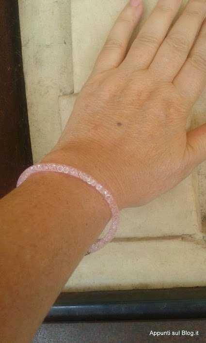 Bracciale di plastica trasparente rosa al polso di una persona.