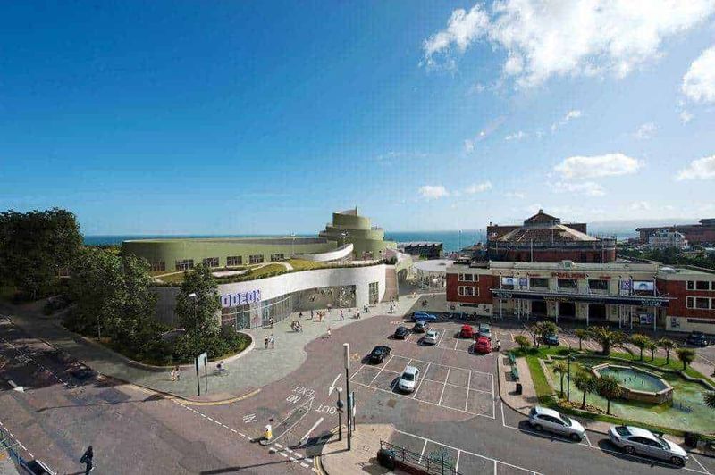 Nuovo centro commerciale al mare con negozi, parcheggi e spazi verdi, vista panoramica e area relax, ideale per shopping e tempo libero vicino alla spiaggia.