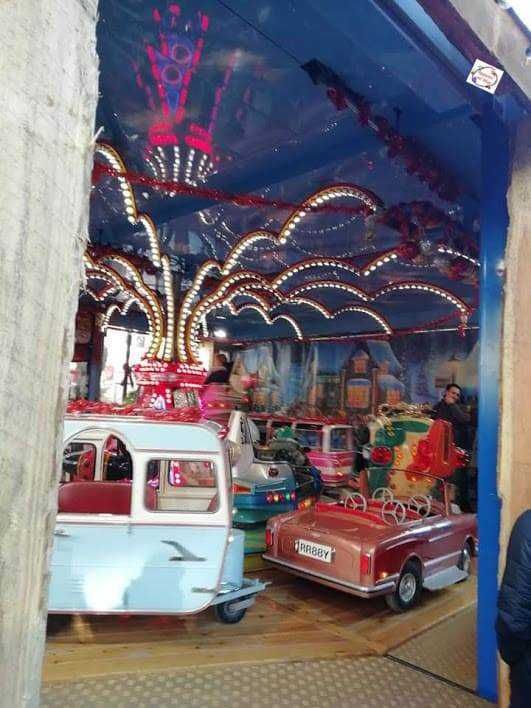 Vetture da luna park vintage con luci colorate, atmosfera festosa e decorazioni fantasiose, ideale per divertimento e intrattenimento enfantile.