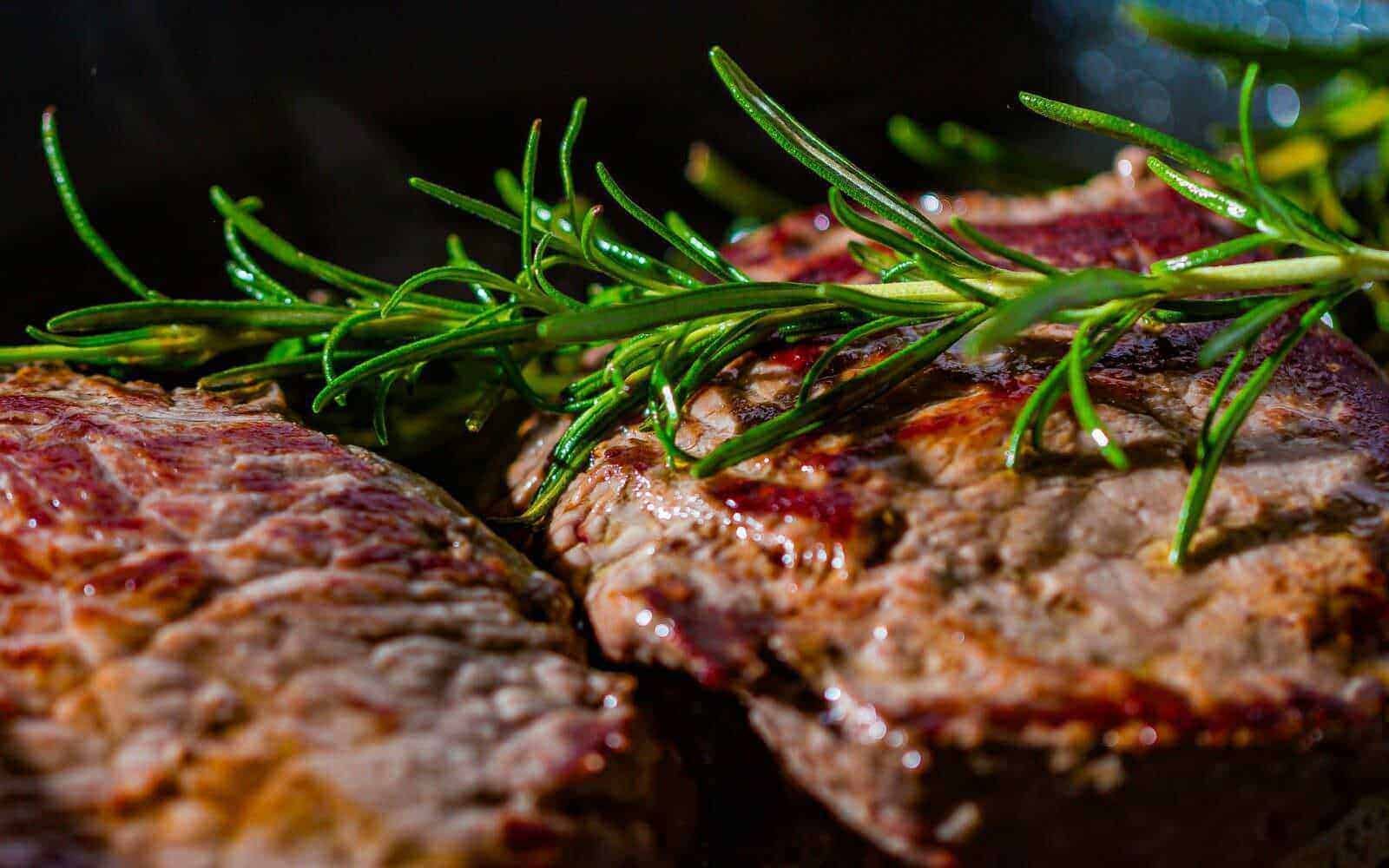 Fette di carne alla griglia con rametti di rosmarino freschi, perfette per un piatto gustoso e aromatico. Ideali per cene estive o barbecue con sapori intensi e autentici.