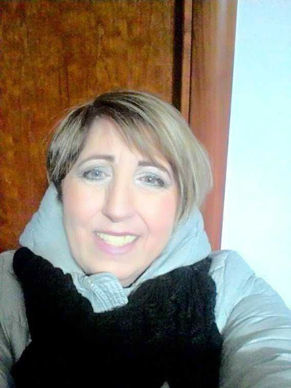 Appunti Sul Blog, immagine di una donna sorridente con cappotto e sciarpa, ripresa in interni, stile casual e amichevole, perfetta per contenuti di lifestyle e blogger.