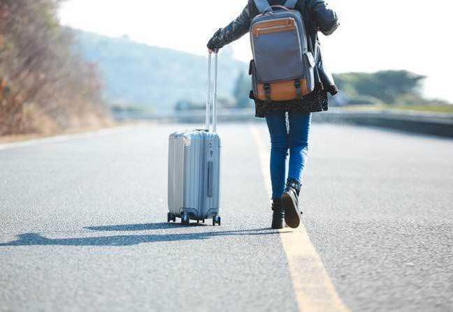 Valigia trolley e zaino da viaggio su strada aperta in campagna, concetto di viaggio avventura, trasporto leggero, vacanze all'aperto, preparativi per viaggio, escursione estiva, itinerario turistico.