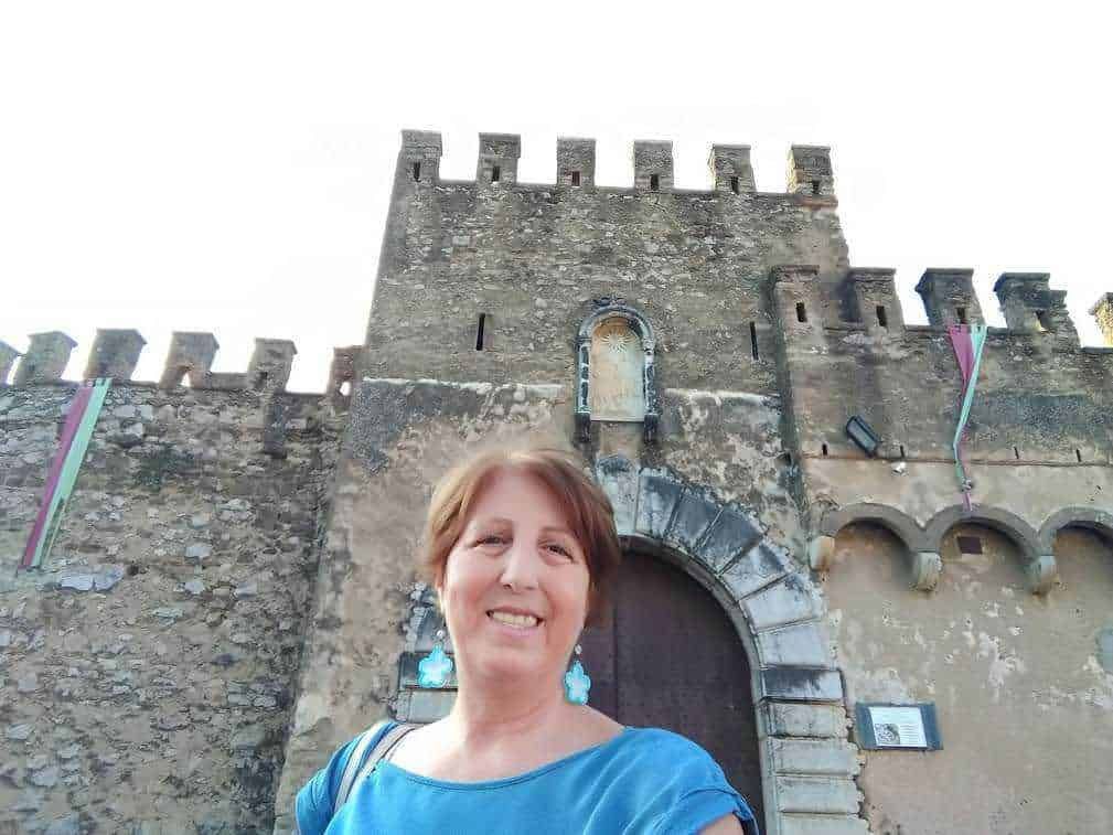 Vecchio castello medievale con mura in pietra e torre, donna sorridente che visita il sito storico, itinerario culturale, architettura storica, turismo in Italia, Appunti Sul Blog.