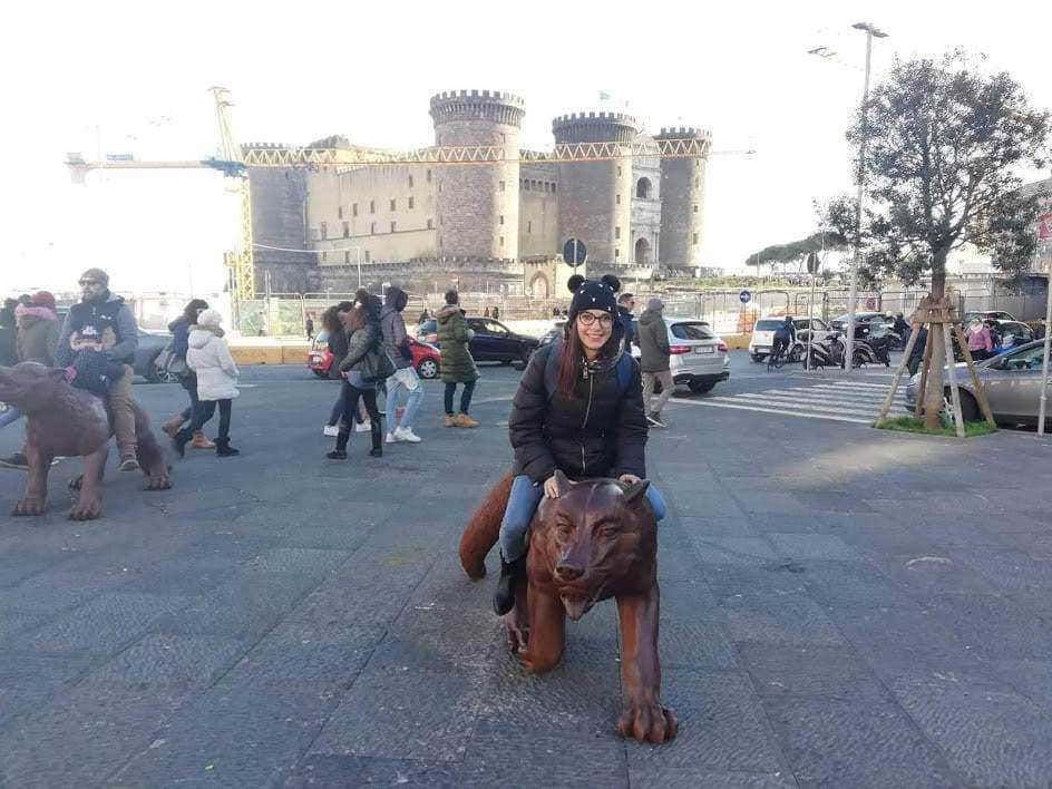 Passeggiata a Roma con donna sorridente su statua di leonessa, sullo sfondo castello medievale e traffico, viaggio, turismo, monumenti, città storica, giovane donna, attrazioni turistiche, cultura italiana, Venezia.