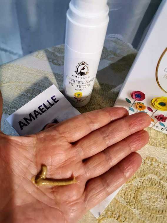 Amamel integrate booster, crema antirughe naturale, in confezione bianca con logo, sulla tavola con fiori e prodotti di bellezza, focus su prodotto per la cura della pelle e routine di bellezza.