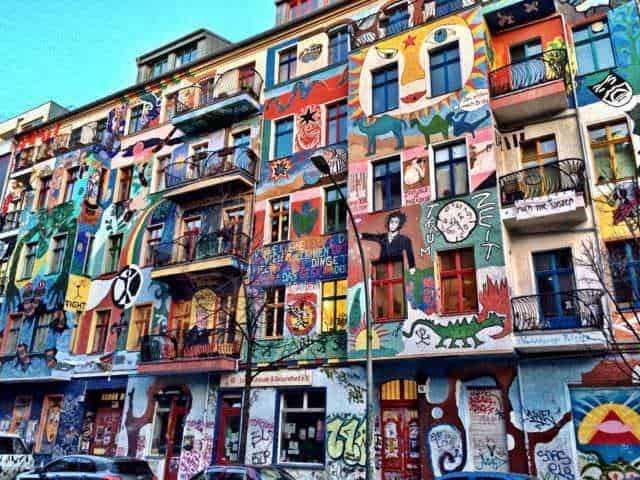 Colorato murale di strada su un edificio a più piani con arte urbana, graffiti e dipinti vivaci che decorano tutta la facciata, creando un ambiente artistico e dinamico.