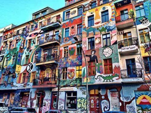 Amanti dell'Arte visiva, scopri 12 città culturali 7 Colorato murale di strada su un edificio a più piani con arte urbana, graffiti e dipinti vivaci che decorano tutta la facciata, creando un ambiente artistico e dinamico.