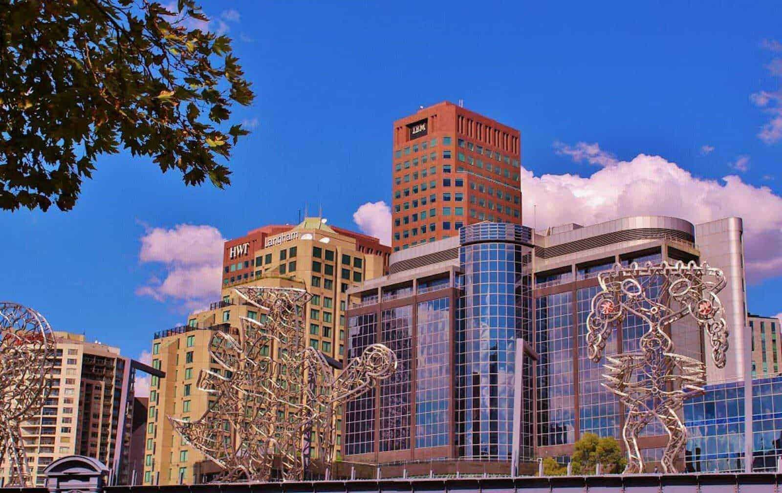 Grattacieli moderni con architettura elegante e sculture artistiche in metallo, città dinamica con edifici alti e cielo azzurro, design urbano e skyline contemporaneo.