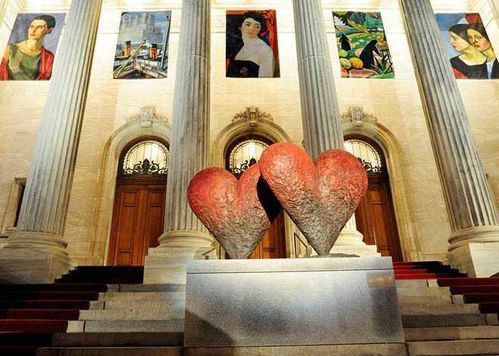 Amanti dell'Arte visiva, scopri 12 città culturali 11 Cuore di pietra artistico al centro di un edificio storico con colonne e dipinti moderni alle pareti, simbolo di amore e arte in un contesto culturale italiano.
