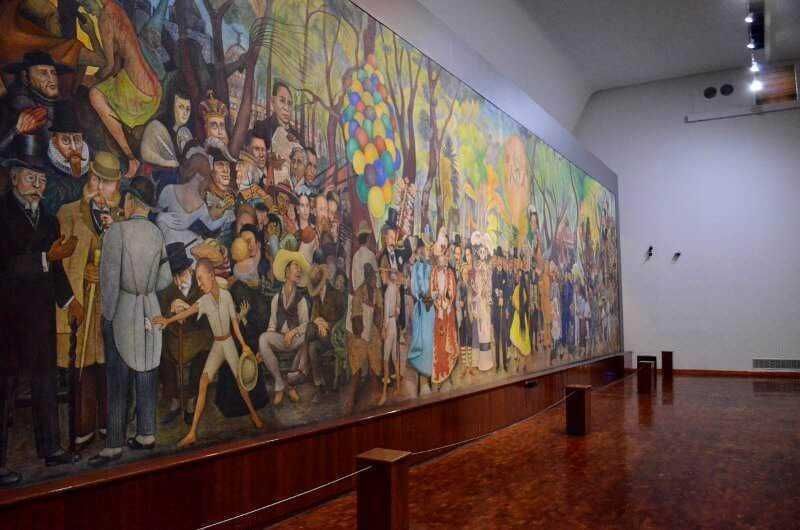 Luci e colori di un grande murale che rappresenta una celebrazione culturale con personaggi storici e civili in un museo d'arte italiana.