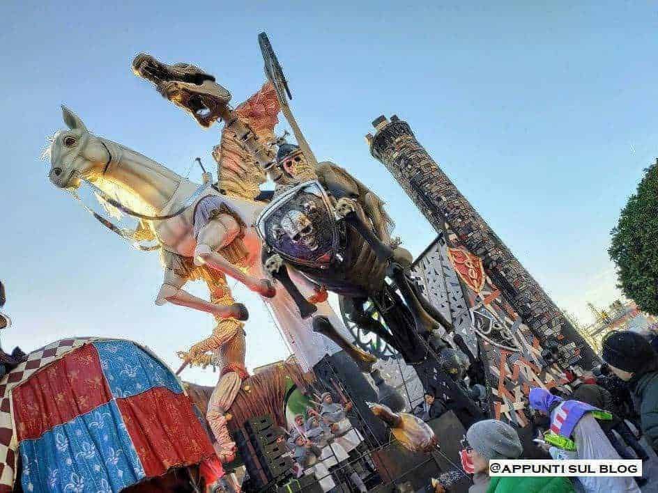 Cavallo di cartapesta e figure di carnevale in una festa tradizionale. Automodelli colorati e decorazioni elaborate creano un'atmosfera festosa e vivace durante l'evento.