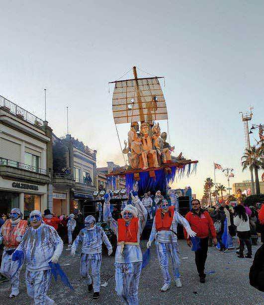 Carro allegorico su strada con personaggi vestiti da clown, sfilata di Carnevale, festa tradizionale, divertimento per tutta la famiglia, decorazioni colorate, cultura popolare, evento esterno.