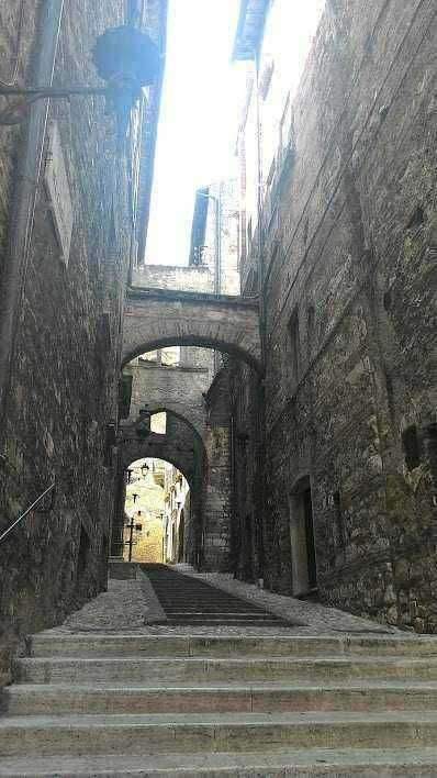 Immagine di una strada antica con scale di pietra tra edifici storici in pietra, in un suggestivo borgo italiano, con archi e vicoli caratteristici, perfetta per appunti sul blog di viaggi e cultura.