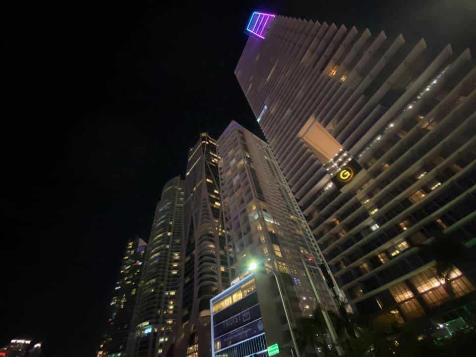 Colorato edificio stile art deco a Miami con palme lungo la strada, cielo azzurro e auto in movimento, ideale per immagini di viaggi, design urbano e destinazioni turistiche.