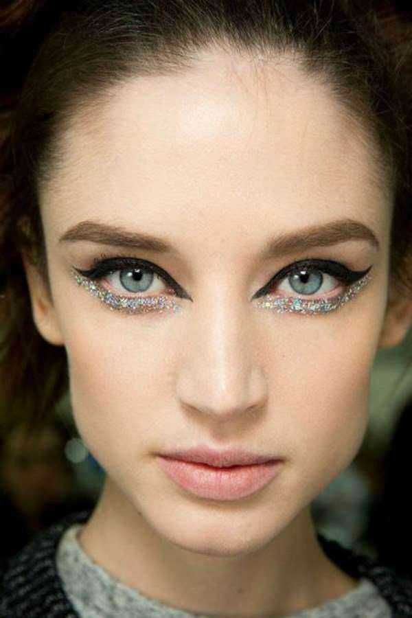 Lucia con trucco occhi speciale, eyeliner nero e dettagli di glitter, ritratto glamour di una giovane donna con pelle chiara e occhi azzurri, moda e make-up.