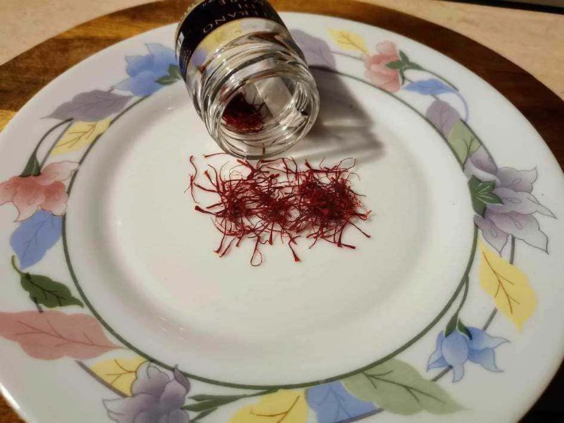 Zafferano di Mare proprietà e usi in cucina 3 Fiocchi di zafferano con contenitore di spezie su piatto decorativo, ingrediente essenziale per cucina gourmet, perfetto per ricette tradizionali e sofisticate.