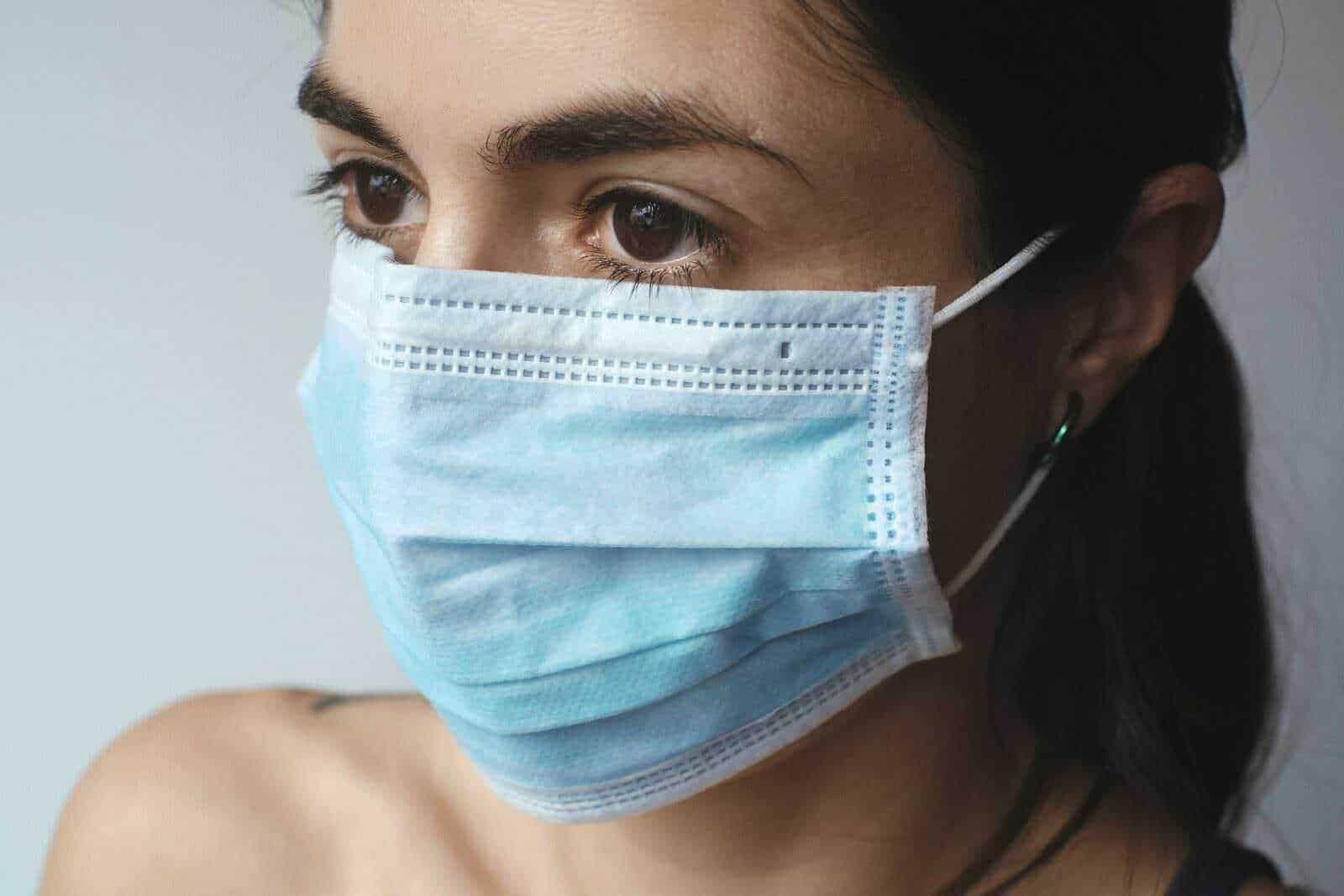 Maschera chirurgica facciale donna in primo piano, prevenzione Covid-19, salute e sicurezza, dispositivo di protezione personale, donna con mascherina blu, igiene e salute in ambienti pubblici.