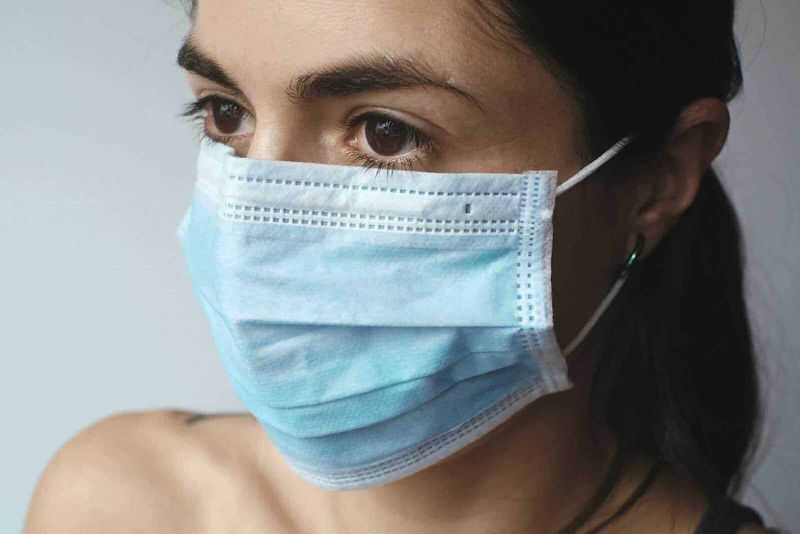 10 terribili pandemie della storia umana, dalla peste al coronavirus 19 4 Maschera chirurgica facciale donna in primo piano, prevenzione Covid-19, salute e sicurezza, dispositivo di protezione personale, donna con mascherina blu, igiene e salute in ambienti pubblici.