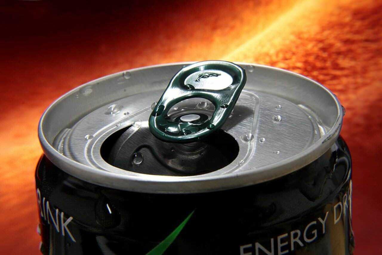Latte energetico in lattina, bevanda a base di energia con zuccheri e caffeina, su sfondo infuocato. Questo prodotto è pensato per migliorare la concentrazione e l'energia durante la giornata.
