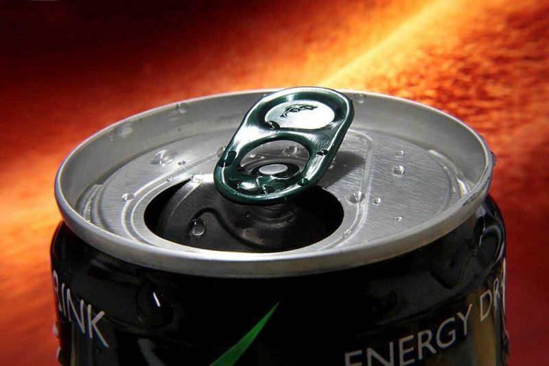Caffeina, quanta in cibi e bevande? 5 Latte energetico in lattina, bevanda a base di energia con zuccheri e caffeina, su sfondo infuocato. Questo prodotto è pensato per migliorare la concentrazione e l'energia durante la giornata.