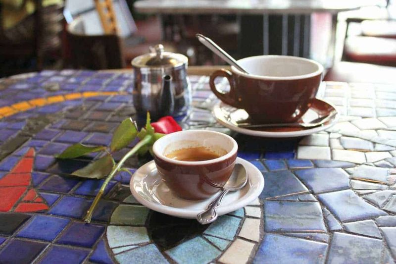 Tazzine di caffè su un tavolo decorato con mosaico colorato in un caffè all'aperto.