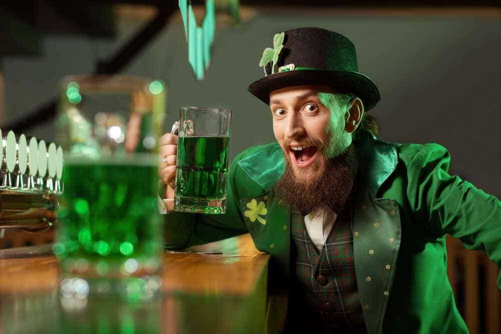 Festeggiato con brindisi in stile irlandese, uomo con cappello di folle e abbigliamento verde tradizionale, atmosfera allegra e decorazioni a tema Saint Patrick's Day.