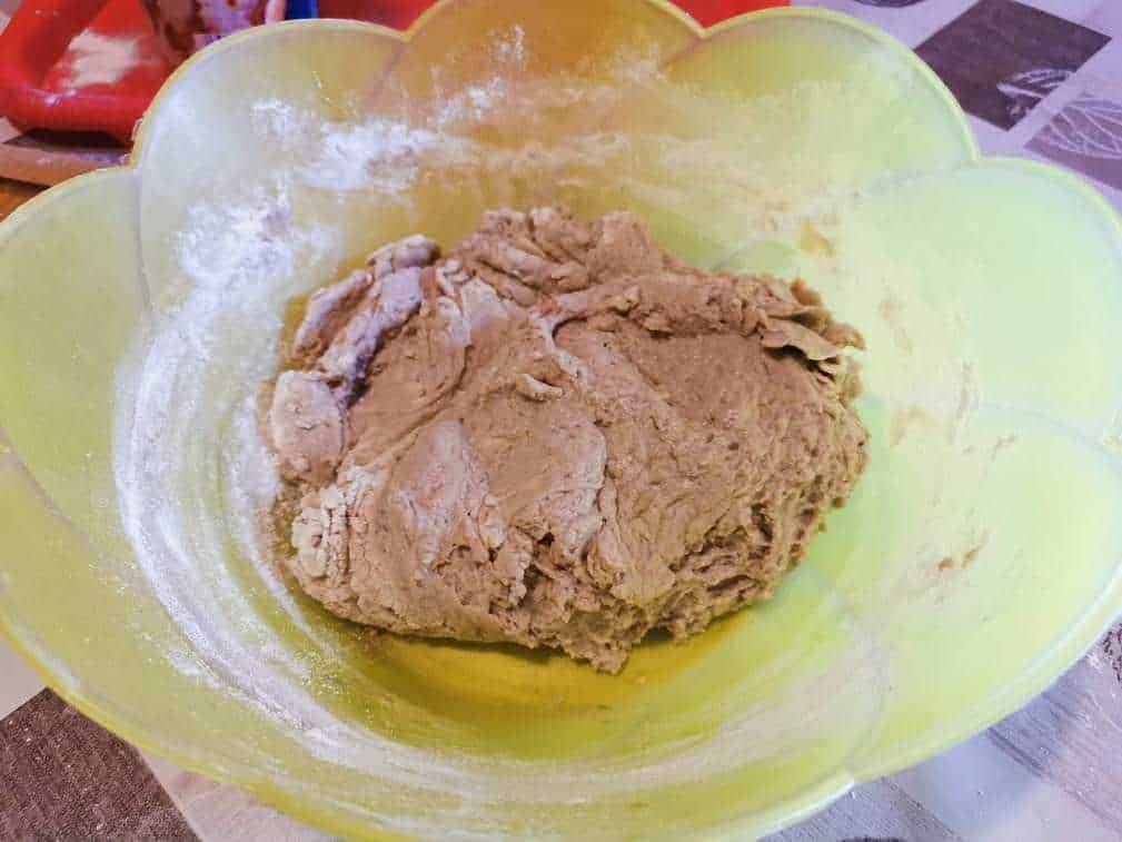 Impasto per pane fatto in casa con farina e acqua in una ciotola verde brillante, pronto per essere lavorato e cotto.