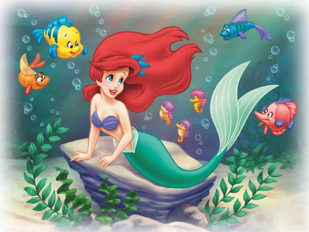 Sirenetta con code colorate e pesci vari attorno in ambientazione sottomarina con piante marine, stile Disney.