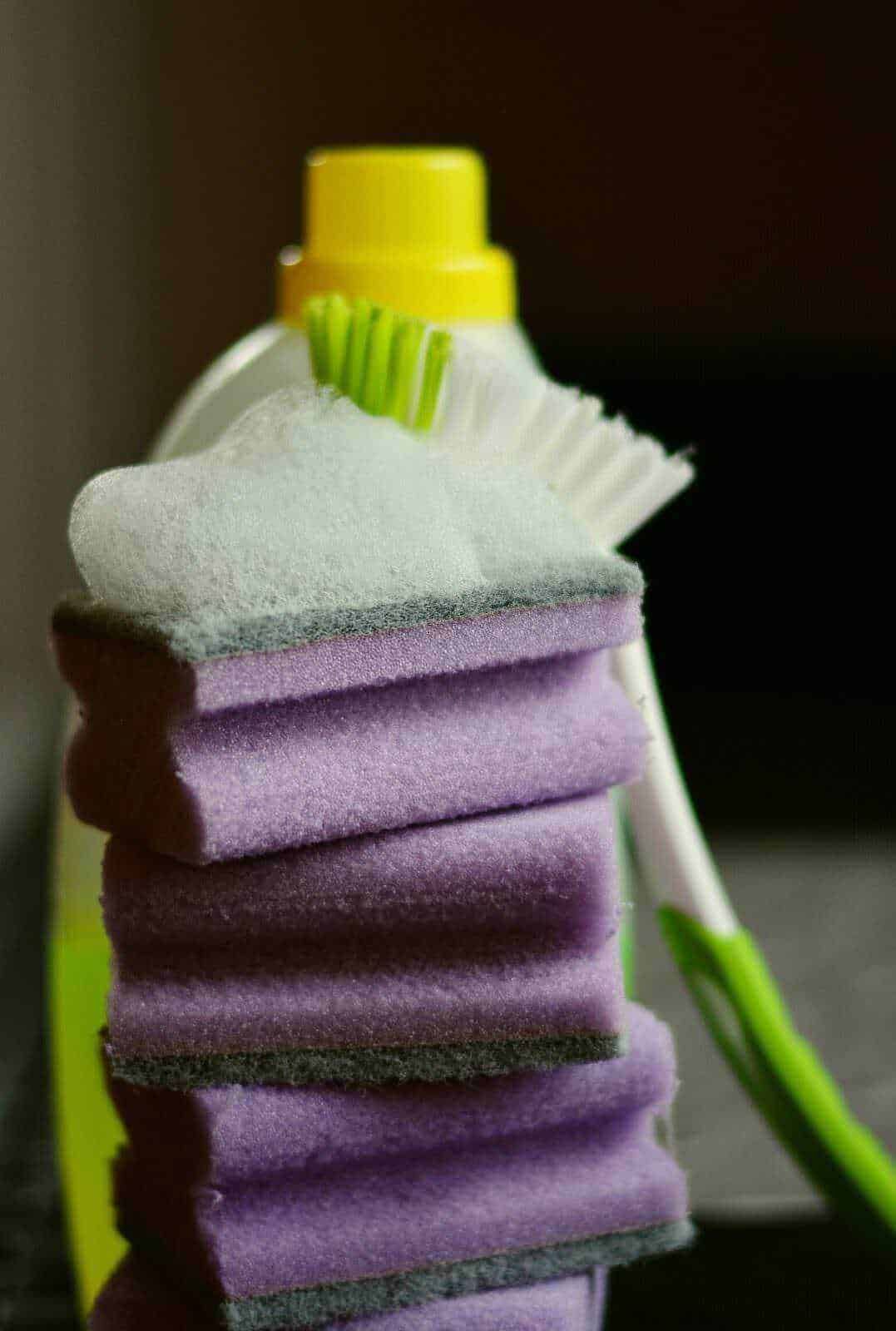 Detersivo liquido per bucato con spugne e spugnetta, evidenziando l'igiene e la cura dei capi di abbigliamento. Ideale per lavaggi efficaci e pratici in casa.