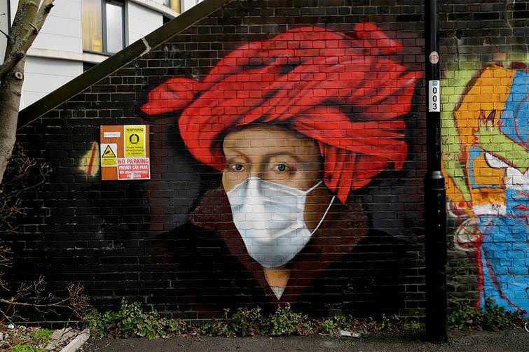 Occhi umani visibili sotto una mascherina, arte di street art su muro di mattoni, ritratto di donna con scialle rosso, graffiti colorato in background, murales urbano, art street, espressione creativa.
