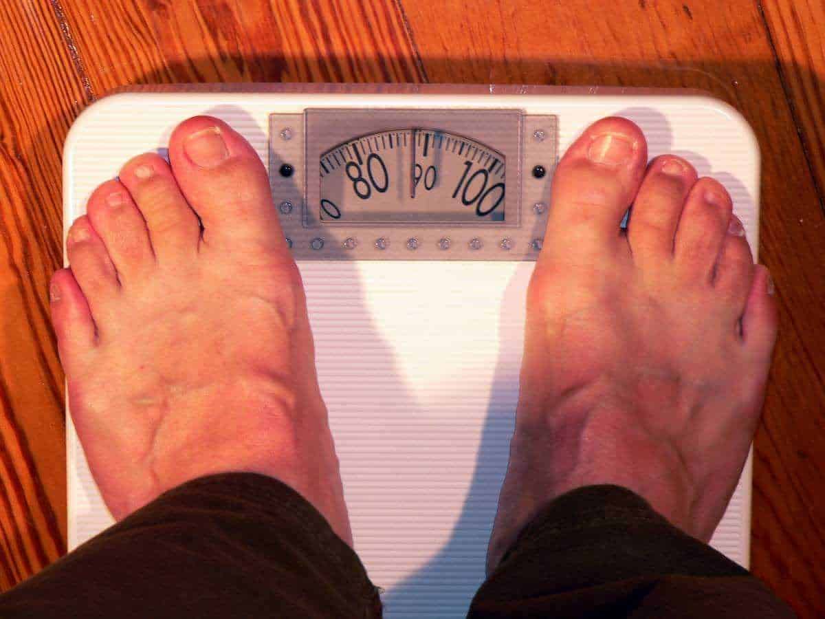 Malattie che causano l'obesità: Bilancia digitale per pesare i piedi di una persona, focus su benessere e controllo peso.