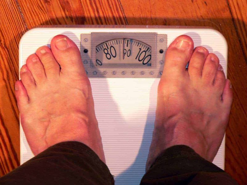 10 malattie che causano obesità e rimedi 2 Malattie che causano l'obesità: Bilancia digitale per pesare i piedi di una persona, focus su benessere e controllo peso.