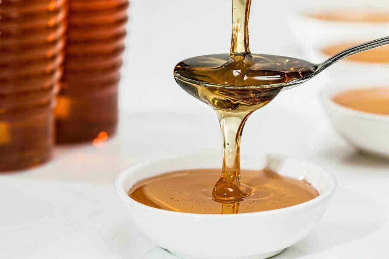 Miele liquido in cucchiaino e ciotola, miele naturale, alimenti dolci, prodotto alimentare biologico, miele di alta qualità, dolcificante naturale, miele crudo e pura, delizia naturale, miele per dolci e tisane.