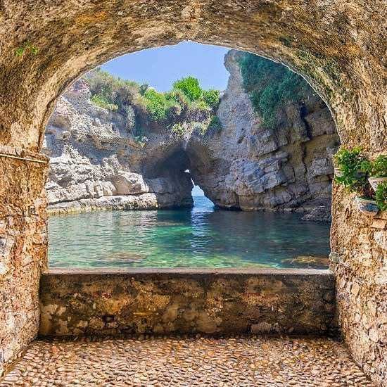 Splendida vista dalla grotta sul mare, con arco naturale e acque cristalline, paesaggio costiero siciliano ricco di colori e natura incontaminata.