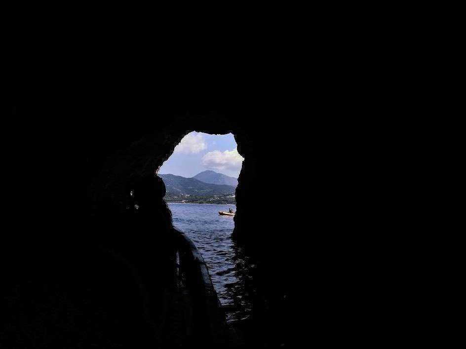 Scorcio di un'escursione in kayak attraverso una grotta naturale sul lago, con vista sulle montagne e il cielo sereno all'esterno.
