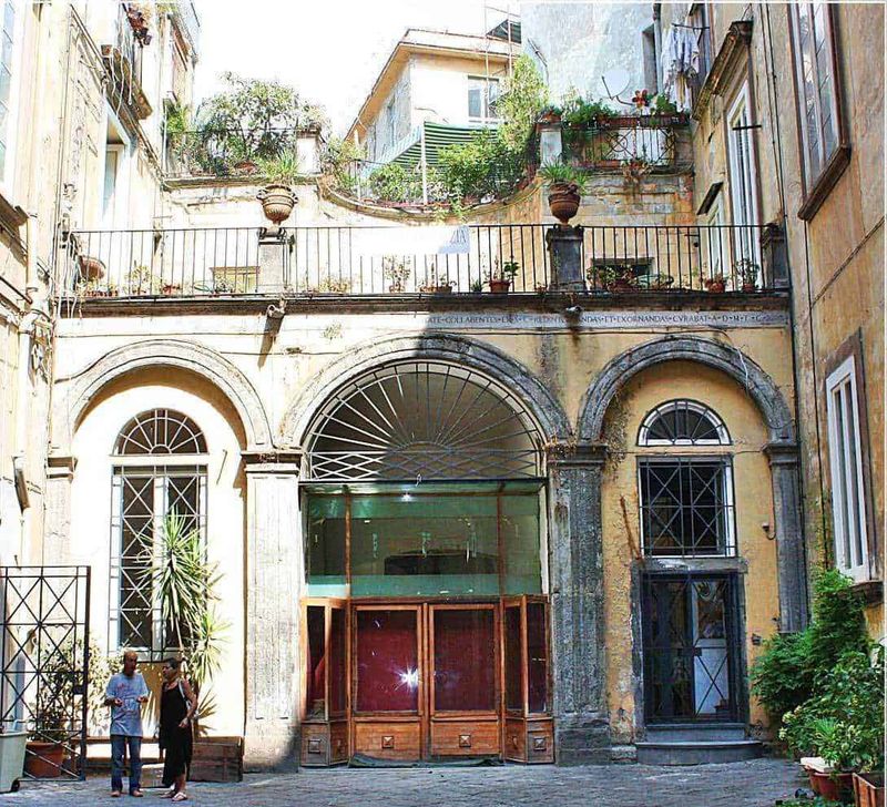 9 Palazzi Neoclassici Napoli e Ville Liberty 4 Benvenuti nel cuore di una storica strada cittadina con facciate colorate e balconi fioriti, perfetta per appunti sul blog di viaggi e cultura italiana. Scene di vita quotidiana e charme medievale in un'immagine autentica.