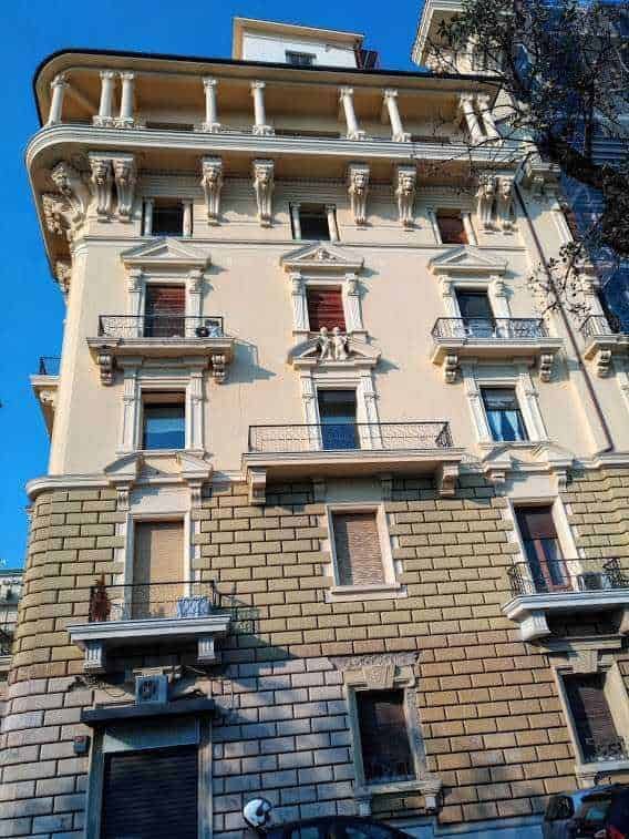 Elegante edificio storico con decorazioni classiche, balconi in ferro battuto e dettagli architettonici raffinati, situato in una zona urbana soleggiata, esempio di architettura italiana traditionale.