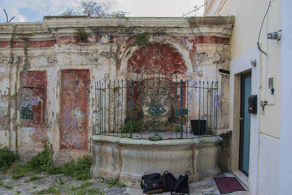 Faro antico con fontana e struttura in pietra, elemento storico e architettonico, caratterizzato da dettagli in stucco e ferro battuto, rappresenta un esempio di patrimonio culturale italiano.